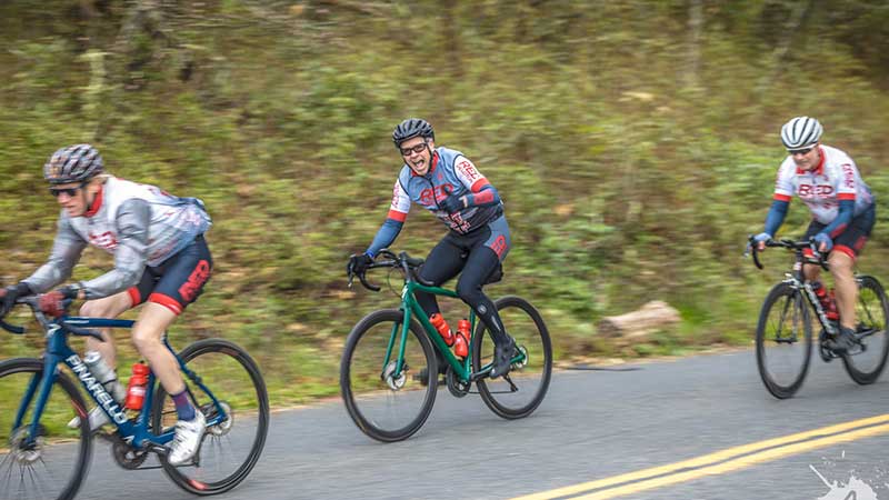 Red Peloton cycling club in Santa Rosa, California. Photo of Red Peloton bike racing team members on a training ride 3 cyclists from the side.